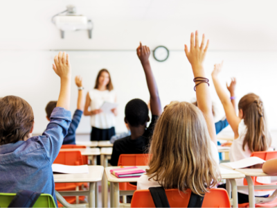 children in class with hands raised