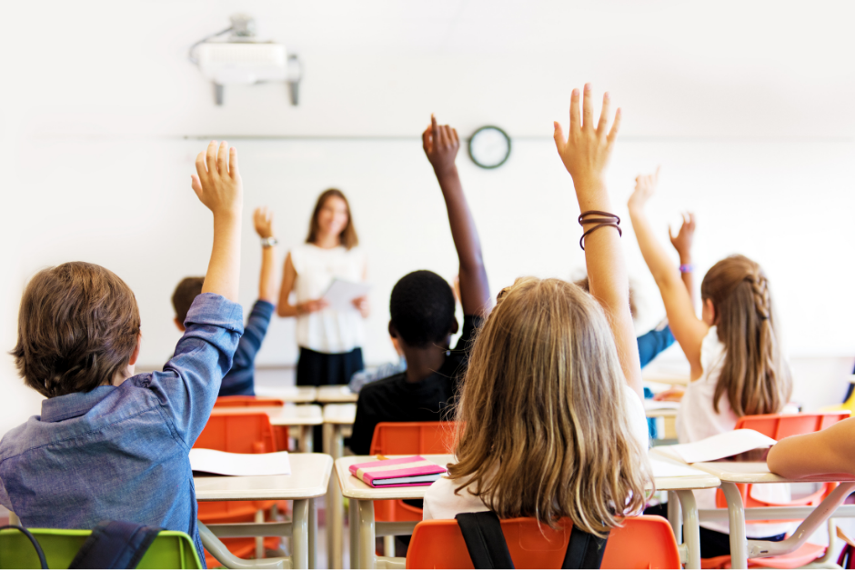 children in class with hands raised